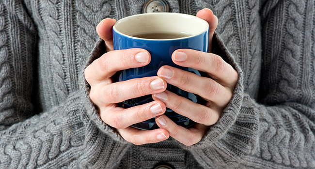 A person holding a filled mug